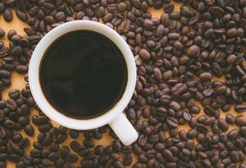 Black coffee in white cup on coffee beans background