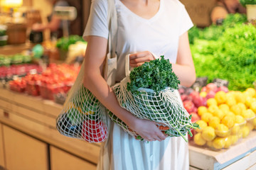 Zero waste concept with copy space. Woman holding cotton shopper and reusable mesh shopping bags...