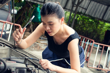 A beautiful woman is fixing broken machine in car