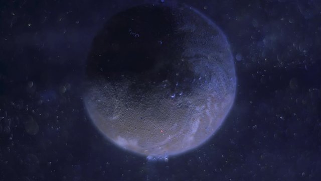 Realistic blue planet rotating around its axis. Millions of dust particles shimmering and flying smoothly in the space. Stars glittering.