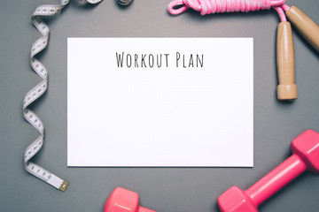 Flat lay shot of workout plan on gray background.