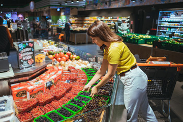 young woman taking berries from store shelf © phpetrunina14