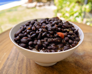 black beans in soup, served in a deep plate on a wooden table