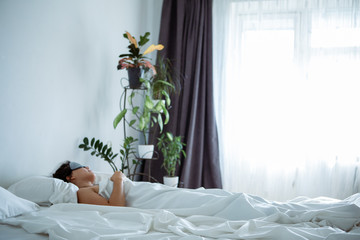 woman sleeping in sleep mask in bed with white sheets