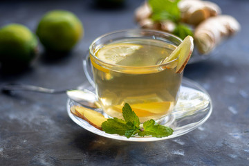 Ginger tea with lemon. Promotes weight loss. Heals colds. Nearby lies a fresh root and lime green. 