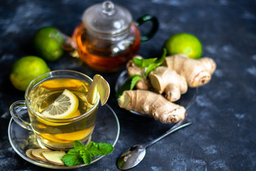 Ginger tea with lemon. Promotes weight loss. Heals colds. Nearby lies a fresh root and lime green. 