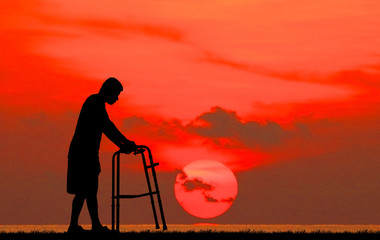 silhouette  Patient walk by using walker on sunrise background.