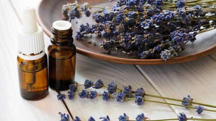 Flat lay composition with bottles of natural lavender essential oil on light stone background