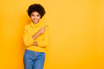 Photo of dark skin lady indicating finger empty space wear warm knitted pullover and jeans isolated yellow background