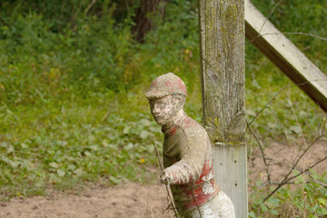 Old broken and weathered statuette of a jockey pointing next to a post