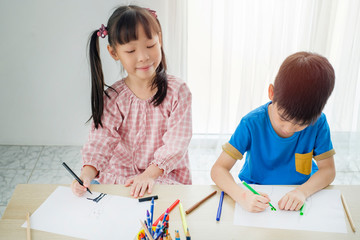 Children drawing piciture with color pencils in classroom