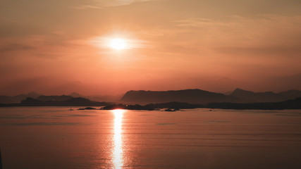 Fototapeta na wymiar Sunrise Over Mountains At Sea