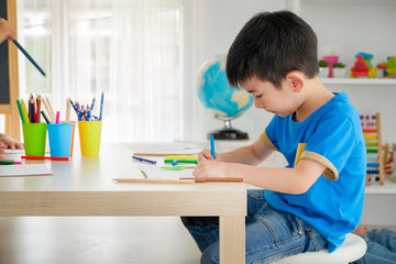 Boy  drawing and doing homework in classroom, children's brand development