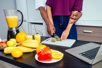cropped shot of dark skinned couple making smoothies, pouring juice