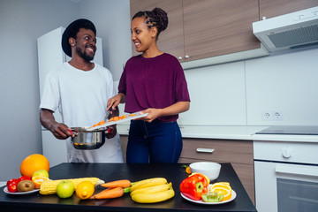 Happy african american love couple cooking fruits salad at kitchen
