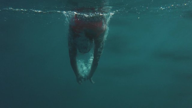 Ragazza con costume arancione si tuffa sott'acqua. Anonima