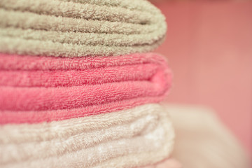 Stack of soft towels staying in bed in hotel room close up. Selective focus.