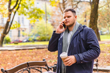 man drinking coffee outdoors autumn season talking on the phone