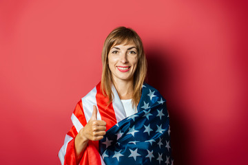 Young girl holds the US flag on a pink background. Concept patriot, holiday, independence day, memorial day, US visa, emigration to USA, education in USA