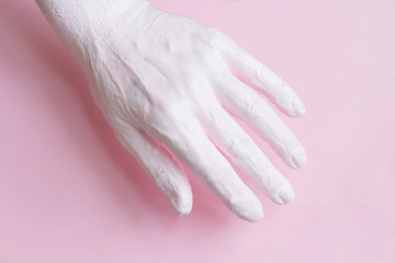 Female hand covered with paint on pink background abstract concept