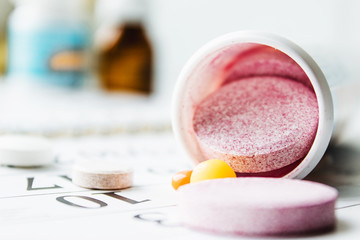Large pink pills or vitamins near a jar on a calendar background.