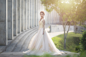 Beautiful portraits with natural light asian woman bride in wedding dress in nature meadow flower,standing in green grassy field in background.