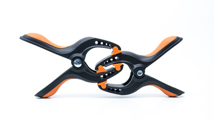 Pair of black and orange color heavy duty plastic spring clamp. Holder or grip equipment for photography and woodworking tools. Isolated on white. Copy space.
