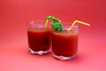 tomato juice in a glass with straws surrounded by tomatoes