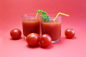 tomato juice in a glass with straws surrounded by tomatoes