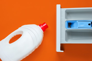 Capacity of washing machine for powder, bottle of washing gel on orange background. Top view, flat lay