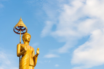 Fototapeta na wymiar Sculpture Golden Buddha Statue standing isolated with Clearly Blue Sky Background