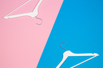 Two white wooden clothes hangers on pastel pink and blue background. Shopping, sale, promo, social media, new season concept