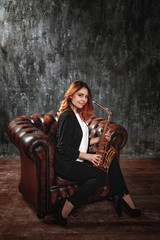 girl holding a saxophone, sitting on a leather armchair
