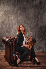 girl holding a saxophone, sitting on a leather armchair