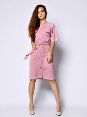 Full length portrait of happy beautiful woman in pink dress posing in studio isolated on white background