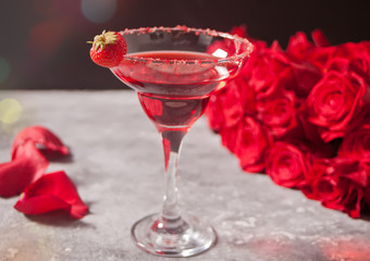 Red exotic alcoholic cocktail in clear glass and red roses for romantic dinner.