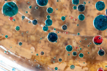 blue and red air bubbles in oil on an orange background close-up