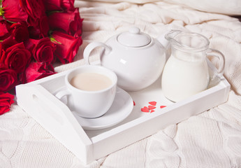 Close up of cup of tea with red roses on the white tray
