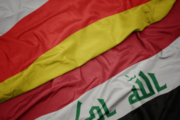 waving colorful flag of iraq and national flag of south ossetia.