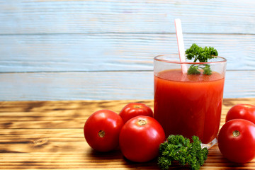 tomato juice in a glass with straws surrounded by tomatoes