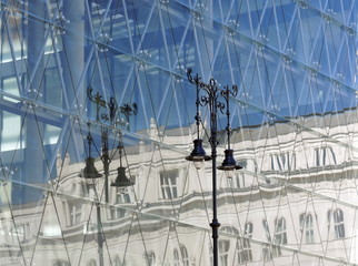 Reflection of old building and street lamp in modern glass building