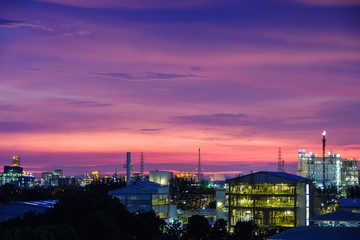 Fototapeta na wymiar Sunset sky view with petrochemical industry estate, glitter lighting factory of petroleum industrial plant on sky sunset background