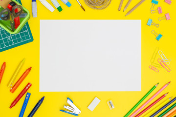 Back to school concept. School supplies. Blank paper page mockup on yellow table background with office tools. Copy space. Flat lay.