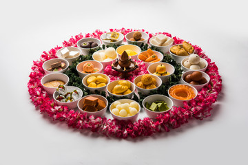 Flower Rangoli with sweets/mithai and diya in bowls for Diwali or any other festivals in India, selective focus