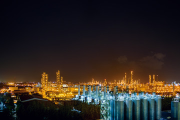 Fototapeta na wymiar Glitter lighting of petrochemical industrial estate at night with polymer storage silo