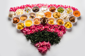 Flower Rangoli with sweets/mithai and diya in bowls for Diwali or any other festivals in India, selective focus