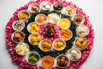 Flower Rangoli with sweets/mithai and diya in bowls for Diwali or any other festivals in India, selective focus