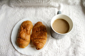 .breakfast with coffee and croissants, on a light background with a notebook