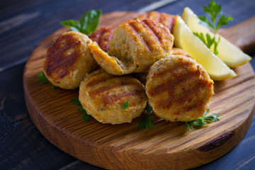 Fish cakes with lemon and herbs. Fish patties on wooden board