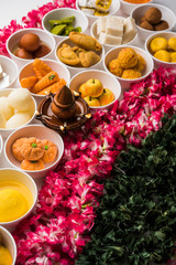 Flower Rangoli with sweets/mithai and diya in bowls for Diwali or any other festivals in India, selective focus